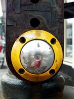 pedestrian safety button in yellow. The button is unperfect condition with a little rust, this are a sign of poorly maintained public facilities. photo
