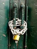 green rusty Gate locked by metal chain and gold padlock. Property real estate and Business Security concept idea. photo