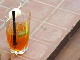 refreshing iced tea with a lychee slice isolated at outdoor park background. Food and beverage concept with copy space for text photo