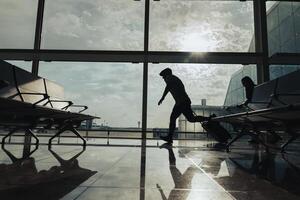 A couple runs with a suitcase through the airport boarding area to avoid missing their flight. photo