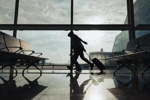 A couple runs with a suitcase through the airport boarding area to avoid missing their flight. photo