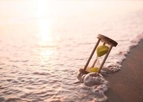 Hourglass on the beach in the sunset time. The concept about countdown to Summer, Travel, Vacation and Relaxation. photo