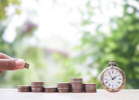 Close up hand putting coin into stack of coins and vintage watch. The concept of saving money for manage time to success business. photo