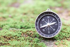 Compass with green moss background. The concept of world tourism day, Searching the right directions and Travel photo