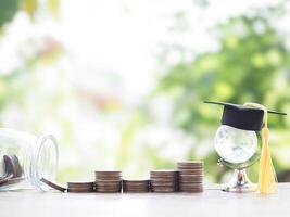 Glass earth globe with graduation hat, stack of coins. The concept of saving money for education, student loan, scholarship, tuition fees in the future photo