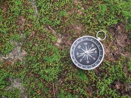 Compass with green moss background. The concept of world tourism day, Searching the right directions and Travel photo