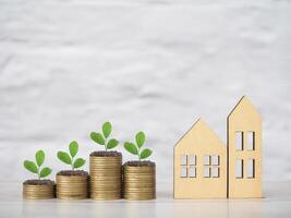 Miniature house and plants growing up on stack of coins. The concept of saving money for house, Property investment, House mortgage, Real estate. photo