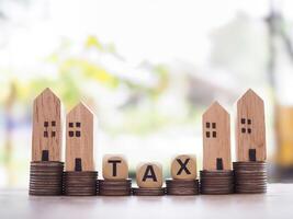 Miniature house and Wooden blocks with the word TAX on stack of coins. The concept of payment tax for house, Property investment, House mortgage, Real estate photo