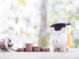 Piggy bank with graduation hat and stack of coins. The concept of saving money for education, student loan, scholarship, tuition fees in the future photo