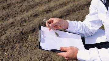 Scientist studying sample of soil in field, close up video