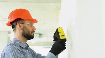 A man builder measures of the vertical deviation of plasterboard wall. Bubble level ruler close up view video