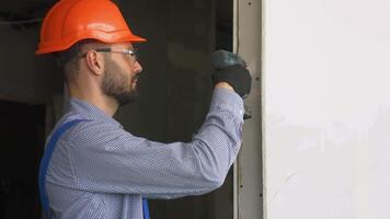 Professional drywall worker or plasterer using cordless electric screwdriver to fix the plasterboard sheets to the metal profiles to build the new wall video