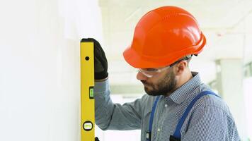 A man builder measures of the vertical deviation of plasterboard wall. Bubble level ruler close up view video