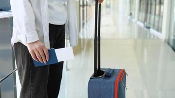 Woman with suitcase holding passport and boarding passes ticket in airport hallway, waiting for document control video