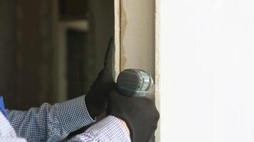Professional drywall worker or plasterer using cordless electric screwdriver to fix the plasterboard sheets to the metal profiles to build the new wall, close up video