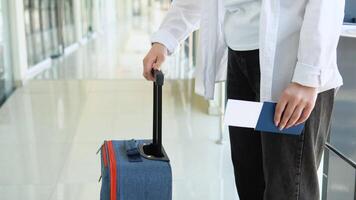Woman with suitcase holding passport and boarding passes ticket in airport hallway, waiting for document control video