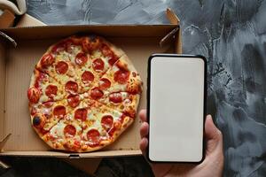 Smartphone with blank screen in hand over pizza in cardboard box. Online food ordering and delivery concept. Generated by artificial intelligence photo