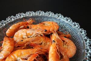 Closeup of cooked shrimp in a glass bowl on a black background. photo