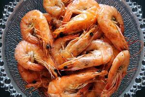 Closeup of cooked shrimp in a glass bowl on a black background. photo