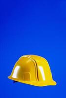 Hard hat for Labour Day concept. Yellow helmet isolated on blue vertical background, 3d render photo