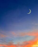 Islamic background with crescent moon in evening with colorful dusk sky. photo