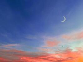 Islamic background with crescent moon in evening with colorful dusk sky. photo