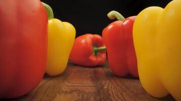 Red and yellow peppers on a wooden surface. The camera moves between the vegetables. Cooking concept. video