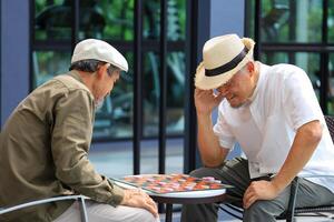 Two senior asian friend are enjoy playing checkers board game at the tropical resort for retirement vacation and luxury leisure recreation travel concept photo