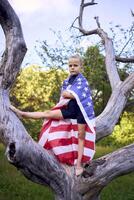 a little 5-year-old gymnast in a black minimalist jumpsuit is practicing with the flag of USA in the garden photo