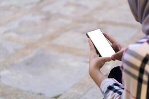 Mockup hijab woman hands holding and using blank screen mobile smart phone clipping path in park outdoor photo