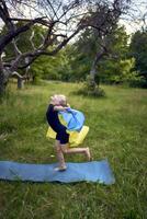 a little 5-year-old gymnast in a black minimalist jumpsuit is practicing with the flag of Ukraine in the garden photo