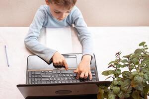 close-up top view, a child in a blue sweater learns to type on a computer, laptop. teaching people at home in bedroom, studying online on computer photo