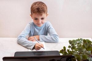close-up top view, a child in a blue sweater learns to type on a computer, laptop. teaching people at home in bedroom, studying online on computer photo