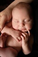 de cerca de un niño en el brazos de un padre en un negro antecedentes. concepto de paternidad y cuidado. minimalista bebé fotografía foto