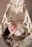 a beautiful baby sleeps in a wicker basket that stands in a wicker tent. beige background with space for text with baby sleeping in a wicker basket photo