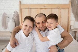 dad with two sons play in a large beautiful bedroom with large windows. happy family in a beautiful light interior. boho style photo