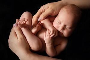 close-up of a child in the arms of a parent on a black background. concept of parenthood and care. minimalistic baby photography photo