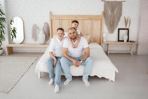 dad with two sons play in a large beautiful bedroom with large windows. happy family in a beautiful light interior. boho style photo