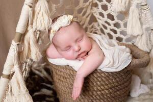 a beautiful baby sleeps in a wicker basket that stands in a wicker tent. beige background with space for text with baby sleeping in a wicker basket. close-up portrait photo