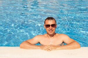 man swims and has fun near a beautiful pool at a resort during vacation. blue background, sea background photo