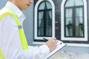 inspector or engineer is inspecting construction and quality assurance new house using a checklist. Engineers or architects or contactor work to build the house before handing it over to the homeowner photo
