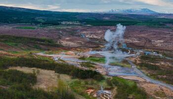 Aerial View of Erupting Geyser in Icelandic Valley Surrounded by Hills photo