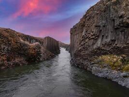 Sunset Over Volcanic Canyon with Deep Blue-Green River in Iceland photo