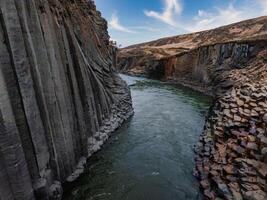 Aerial View of River Flowing Through Basalt Cliffs in Icelandic Canyon photo