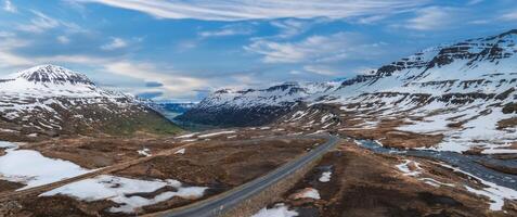 Aerial View of Snow-Capped Mountain Valley with Winding Road in Iceland photo