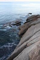 a person standing on a rock overlooking the ocean photo