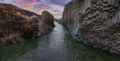 Serene River Flowing Through Basalt Column Canyon Under Vibrant Sky in Iceland photo