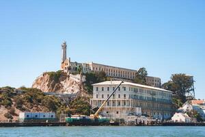 Sunny view of Alcatraz Island in San Francisco Bay. Former federal prison, main cellhouse, lighthouse, and rugged terrain depicted. Isolated beauty captured. photo