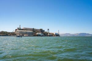 Alcatraz Island in San Francisco Bay, California, USA. View from the water, showcasing the infamous former prison turned museum with a lighthouse, waters, and rolling hills in the background. photo