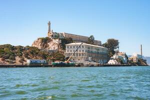 Clear day view of Alcatraz Island in San Francisco Bay, California, USA, showcasing the former prison complex with main cellhouse, lighthouse, dock, and historic structures. photo
